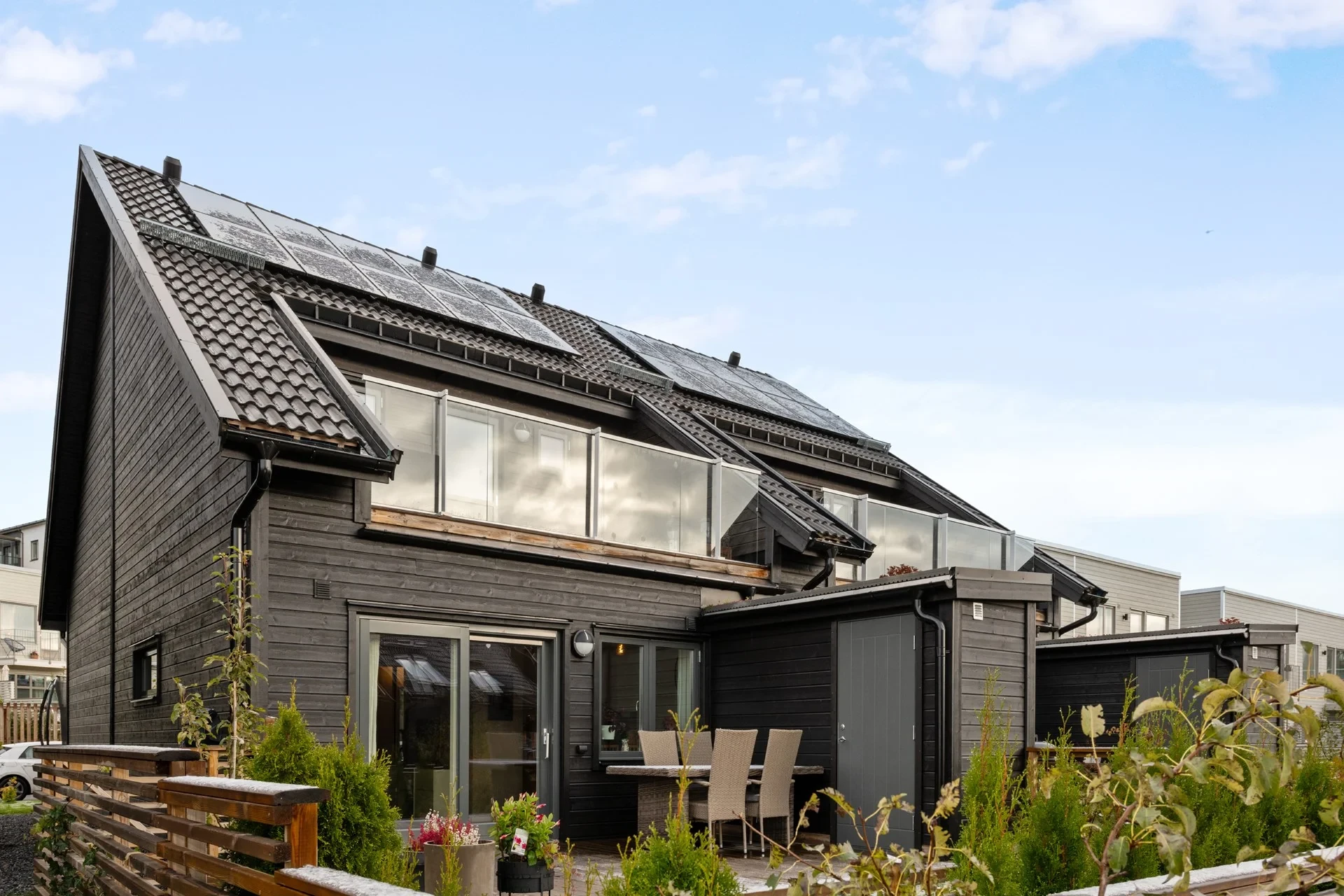 Modernt br-parhus med solpaneler och laddstolpe